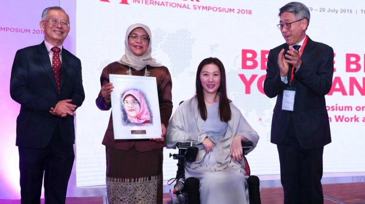 Picture of Mrs Zhang Kaini presenting President Halimah Yacob with her portrait at the International Symposium 2018. Available at https://m.facebook.com/halimahyacob/photos/thank-you-mdm-zhang-kaini-for-the-beautiful-portrait-i-am-touched-to-hear-tha